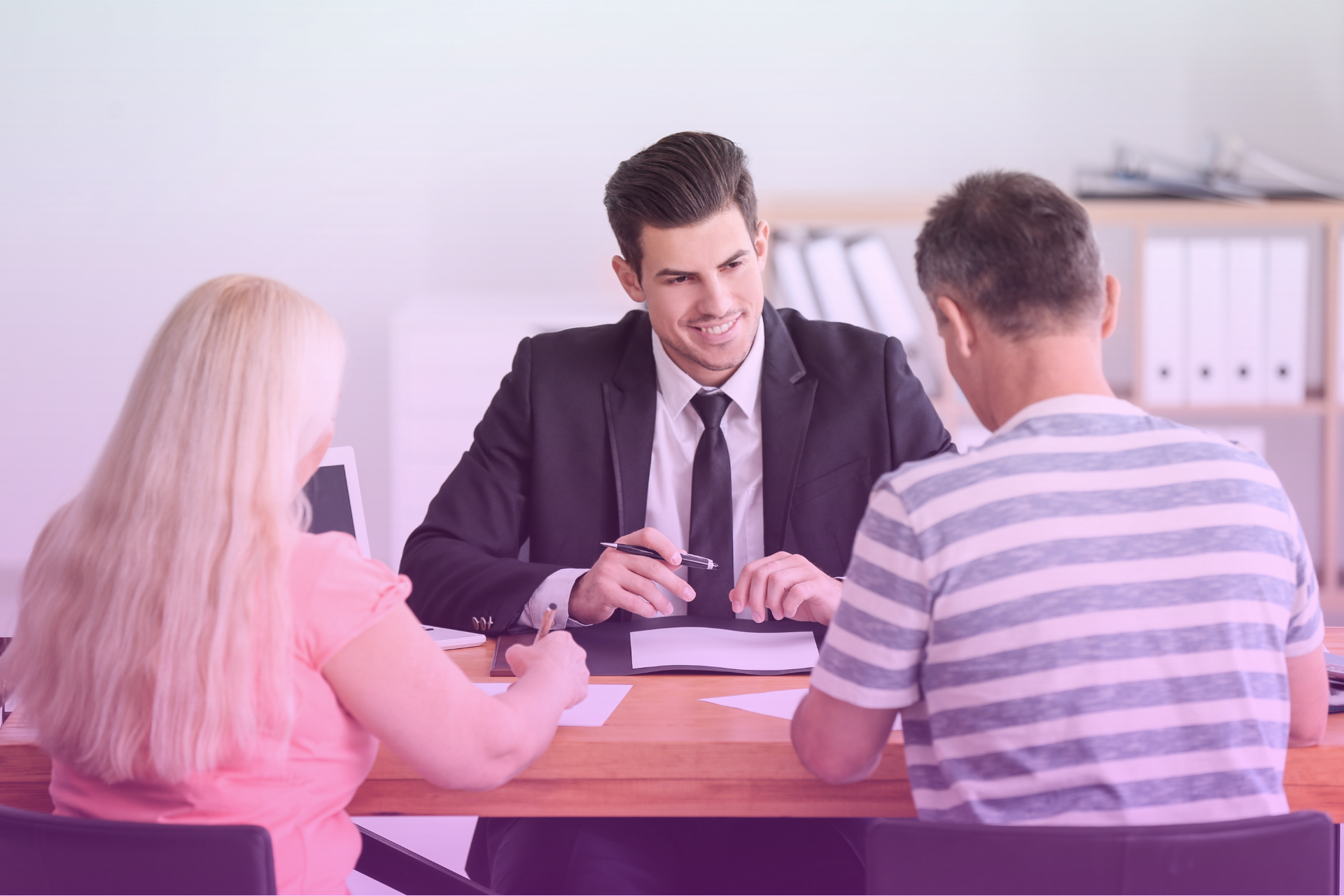 A couple sitting at a table with a lawyer, reviewing legal documents.