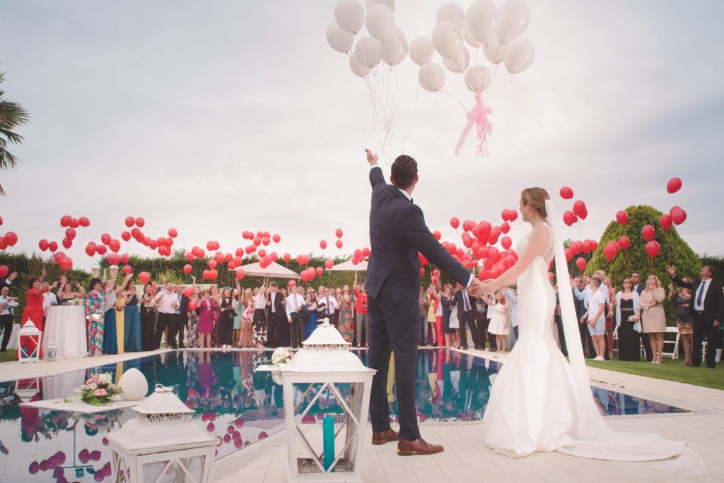 newly married couple and wedding guests releasing balloons
