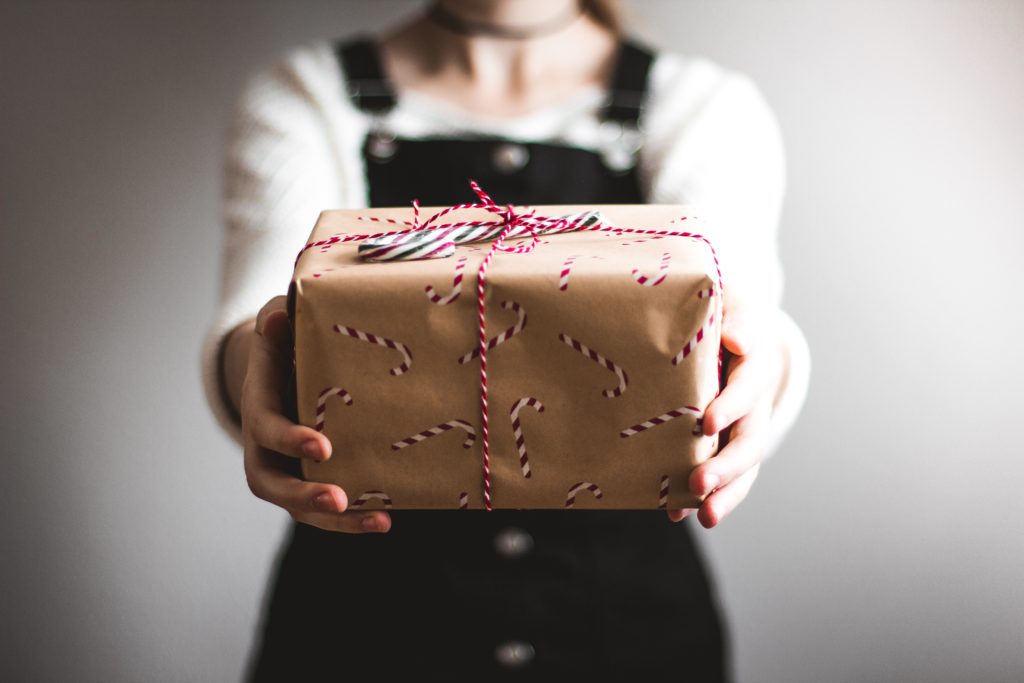girl giving gift wrapped in brown paper and red string