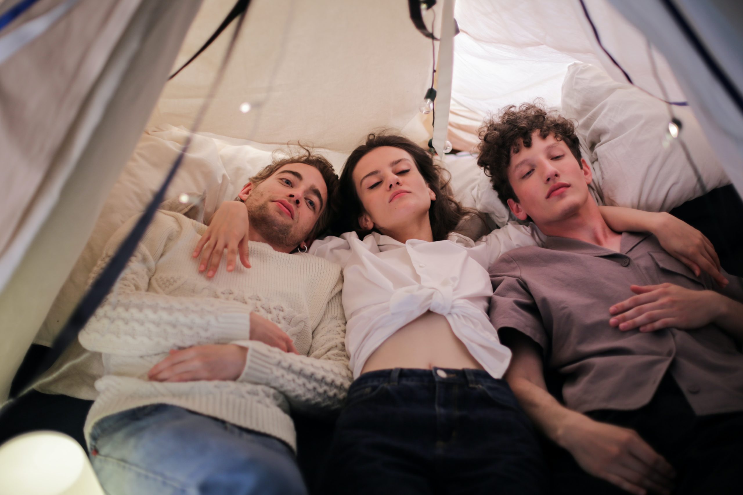 woman with two men embraced in a tent Polyamory And Domestic Partnerships