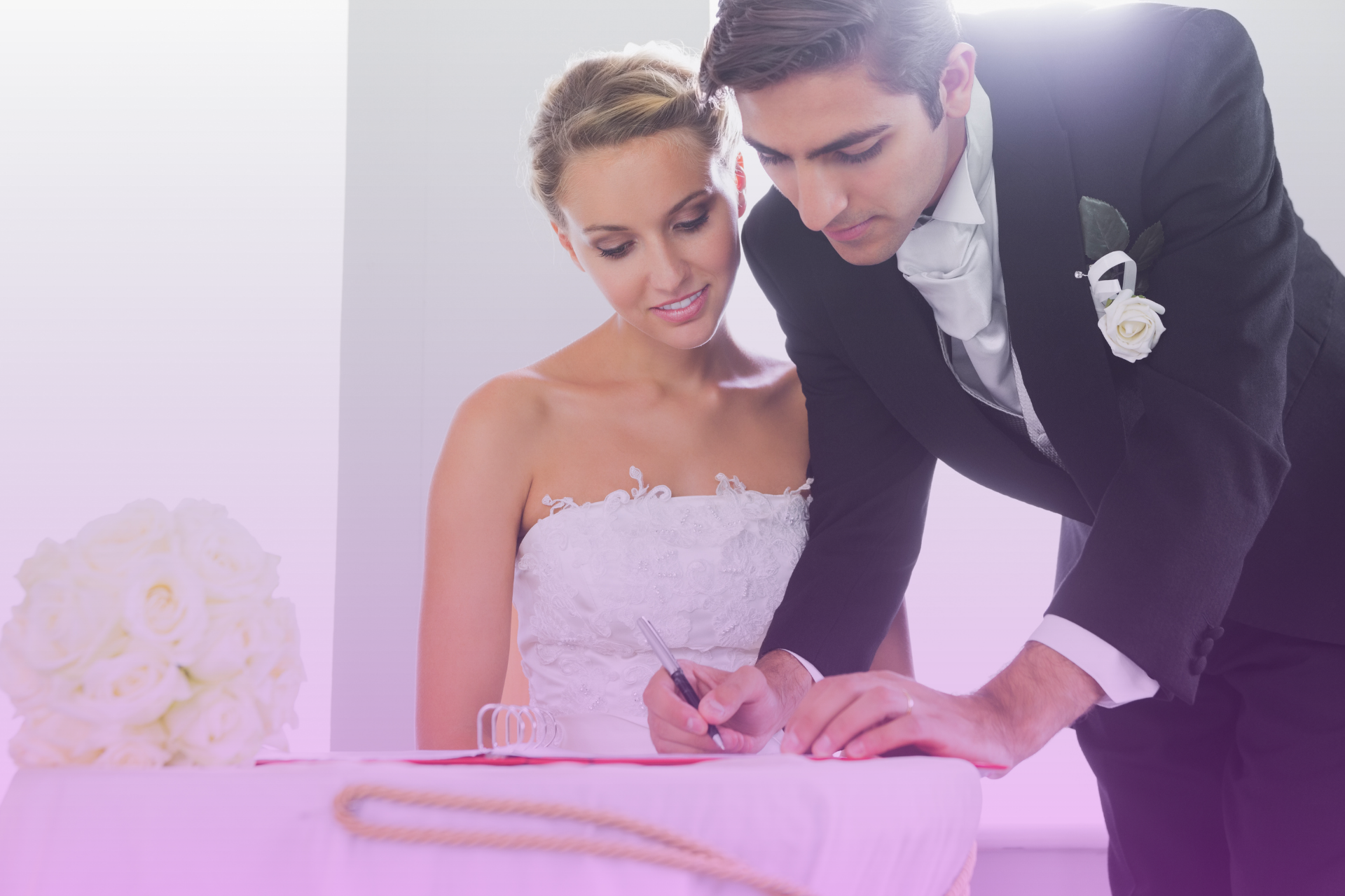Couple sitting at a table, smiling and filling out a marriage license application form
