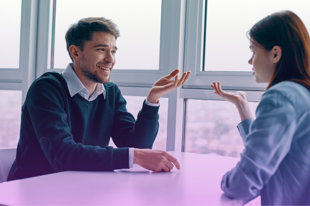 A couple sitting at a table, talking openly and looking at each other.
