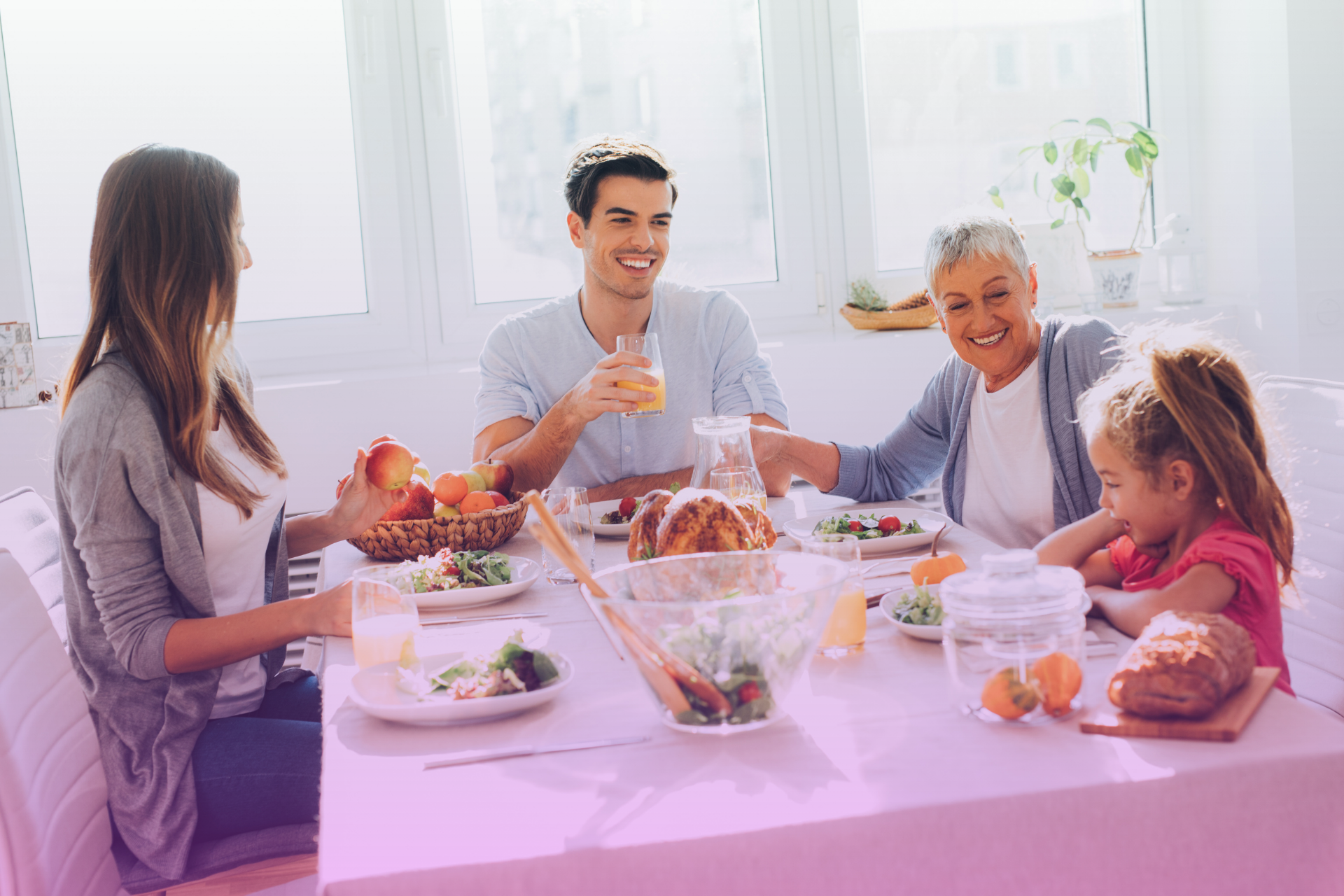 Smiling family enjoying a meal together at a table, including adult children and parents.