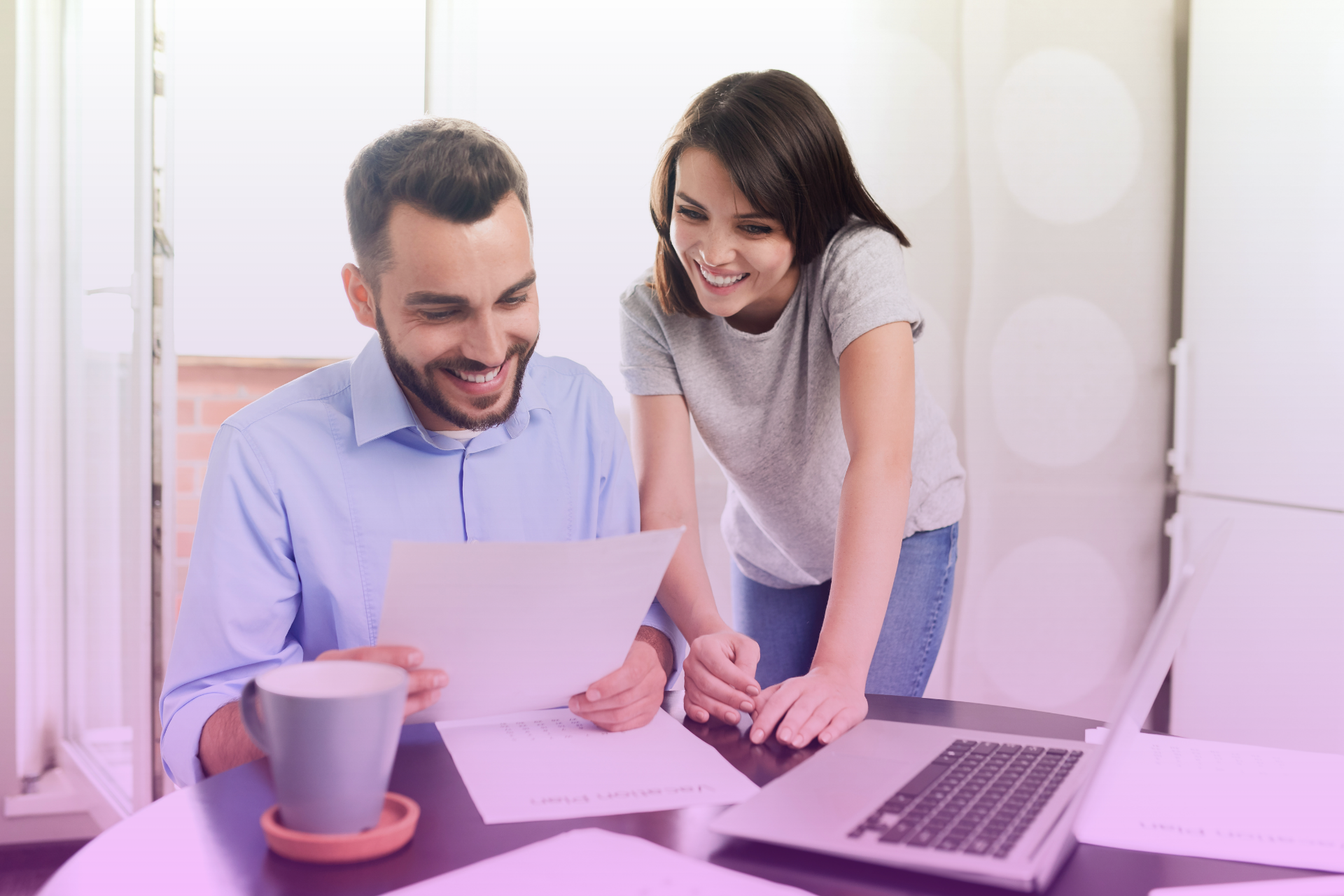 A smiling couple sits at a table reviewing tax documents together.