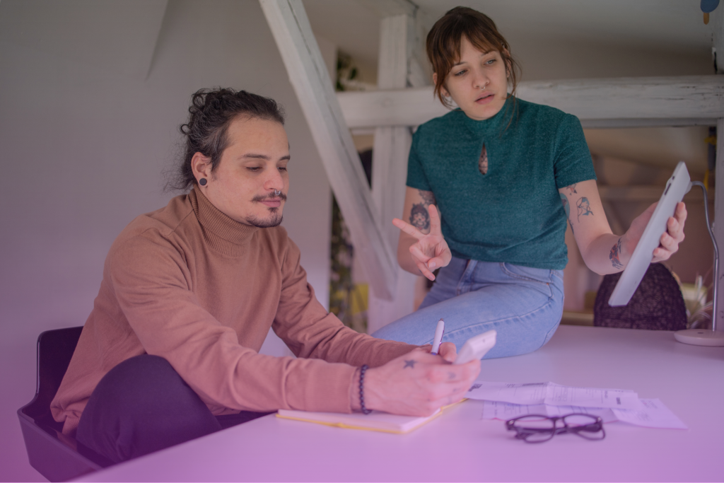 A happy couple sitting at a table, reviewing financial documents and smiling at each other.