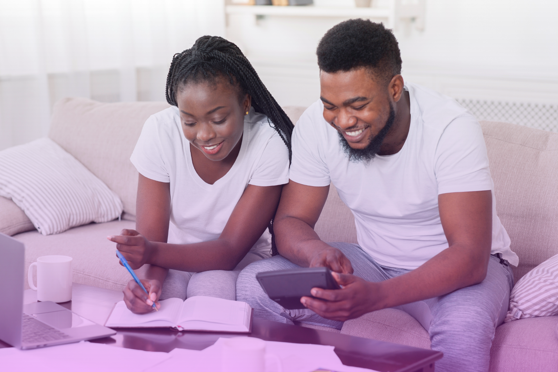Happy couple sitting at a table reviewing their finances on a laptop.