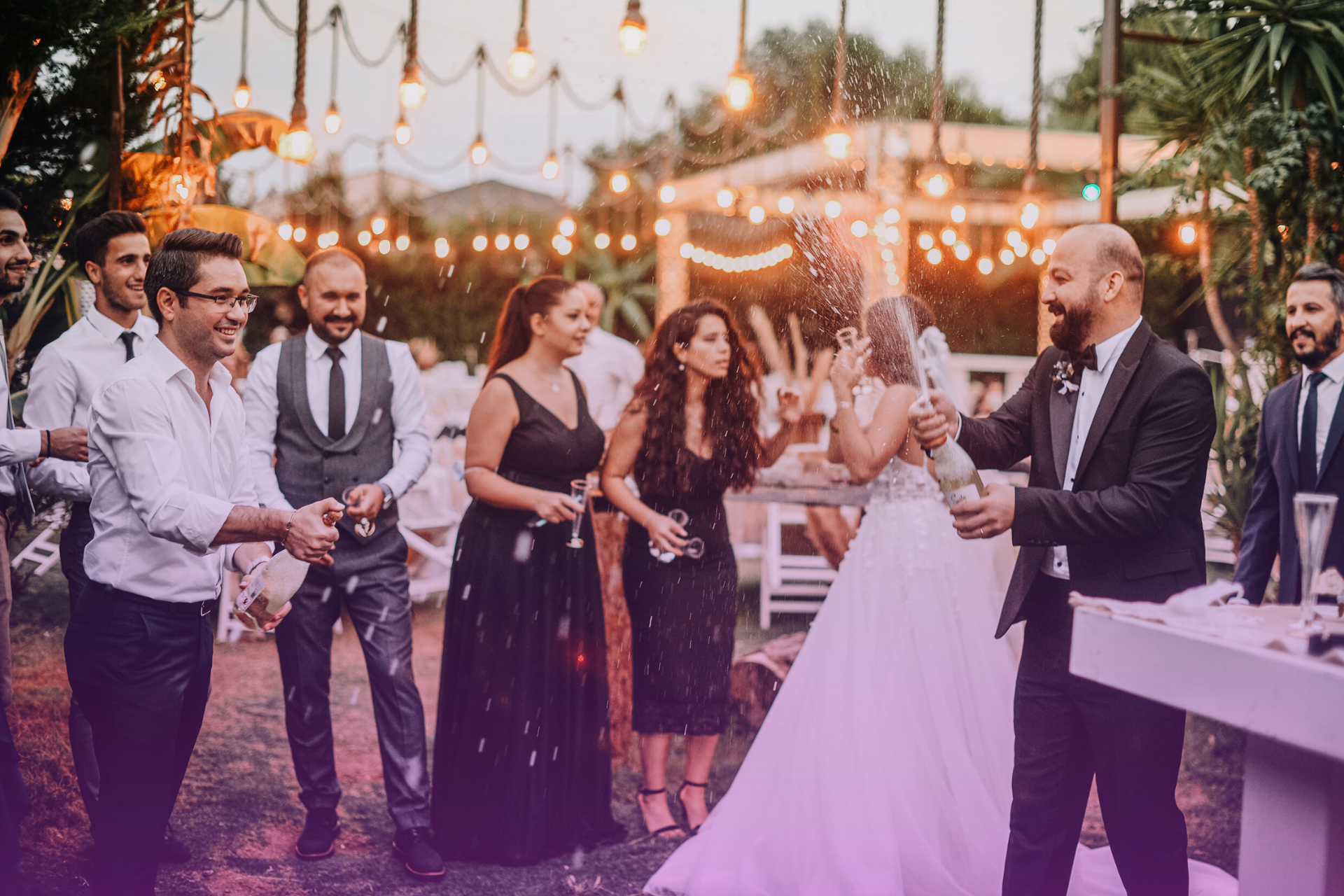A diverse group of wedding party members celebrate together with laughter.