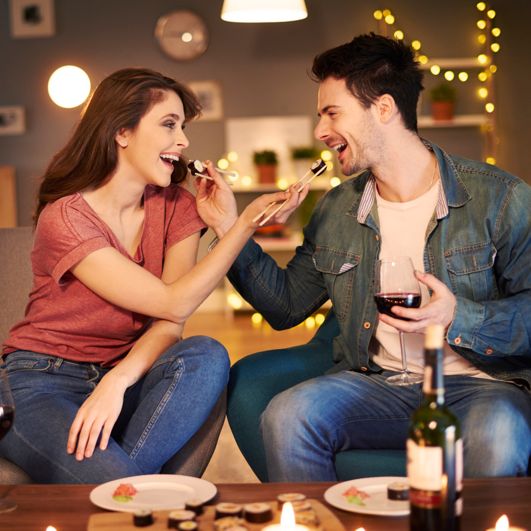 couple at romantic dinner eating sushi and drinking wine while laughing