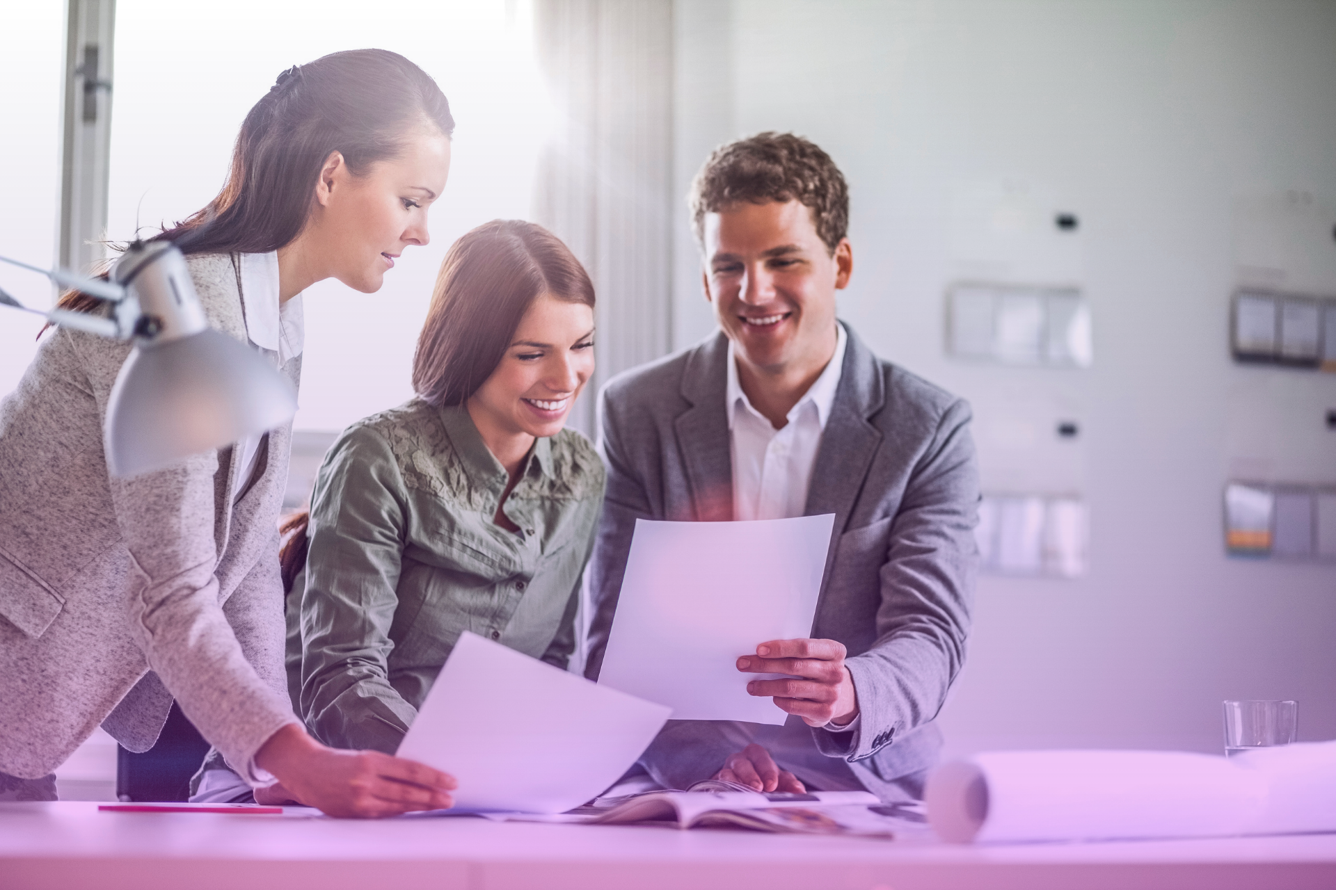 happy-couple-reviewing-documents Smiling couple reviewing documents with a lawyer at a table.