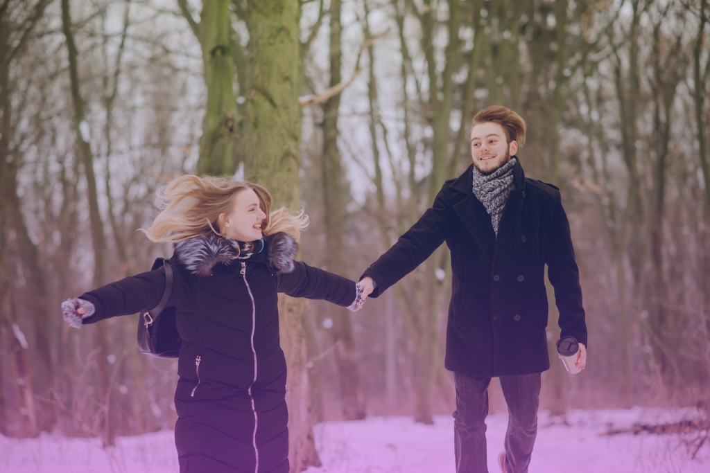 A happy couple holding hands and smiling in the breathtaking Alaskan landscape.