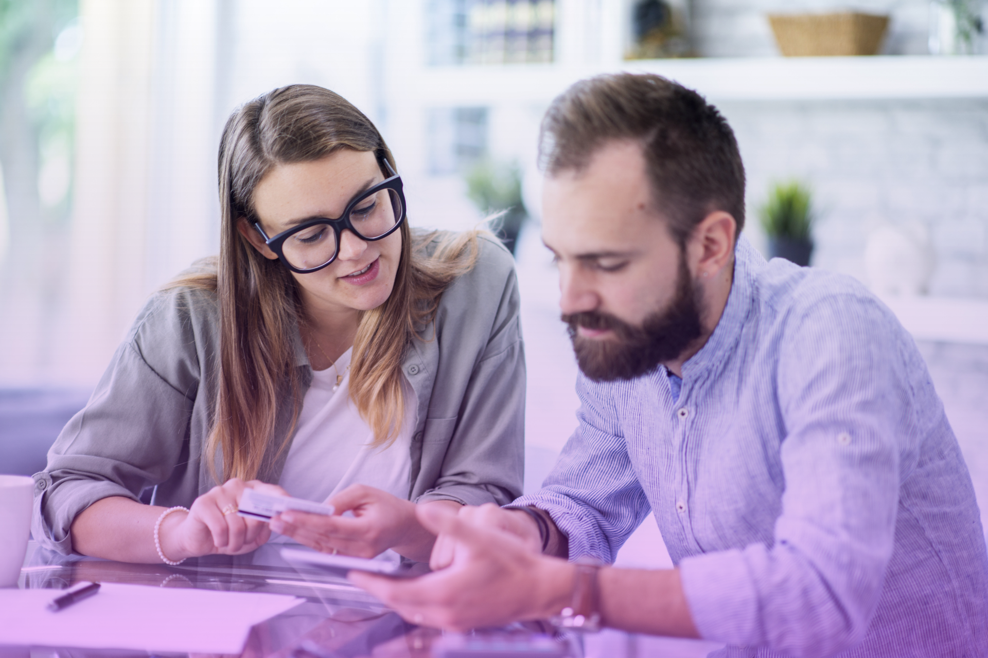 Happy couple talking about finances at a table, considering a prenuptial agreement.