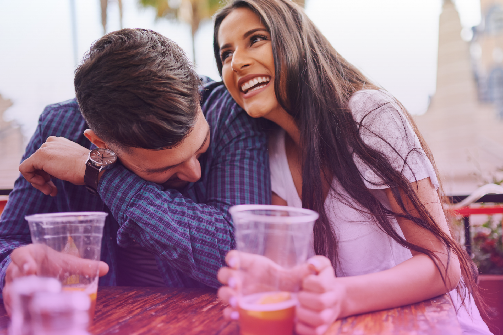 Couple laughing together playfully, with bright smiles and joy on their faces.