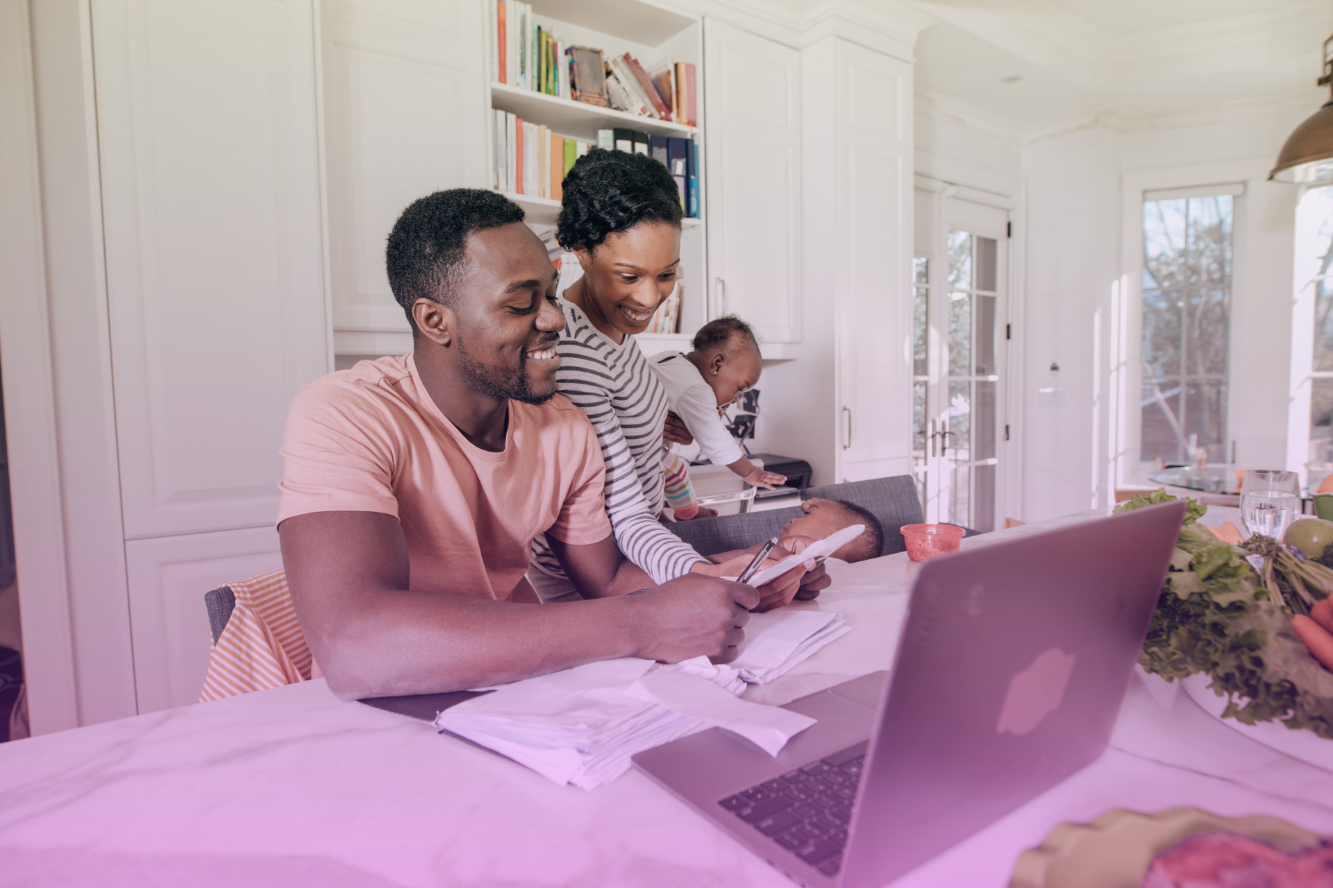 A family sitting around a dining table, collaboratively managing their finances on a laptop by organizing spreadsheets and discussing their budget plans.