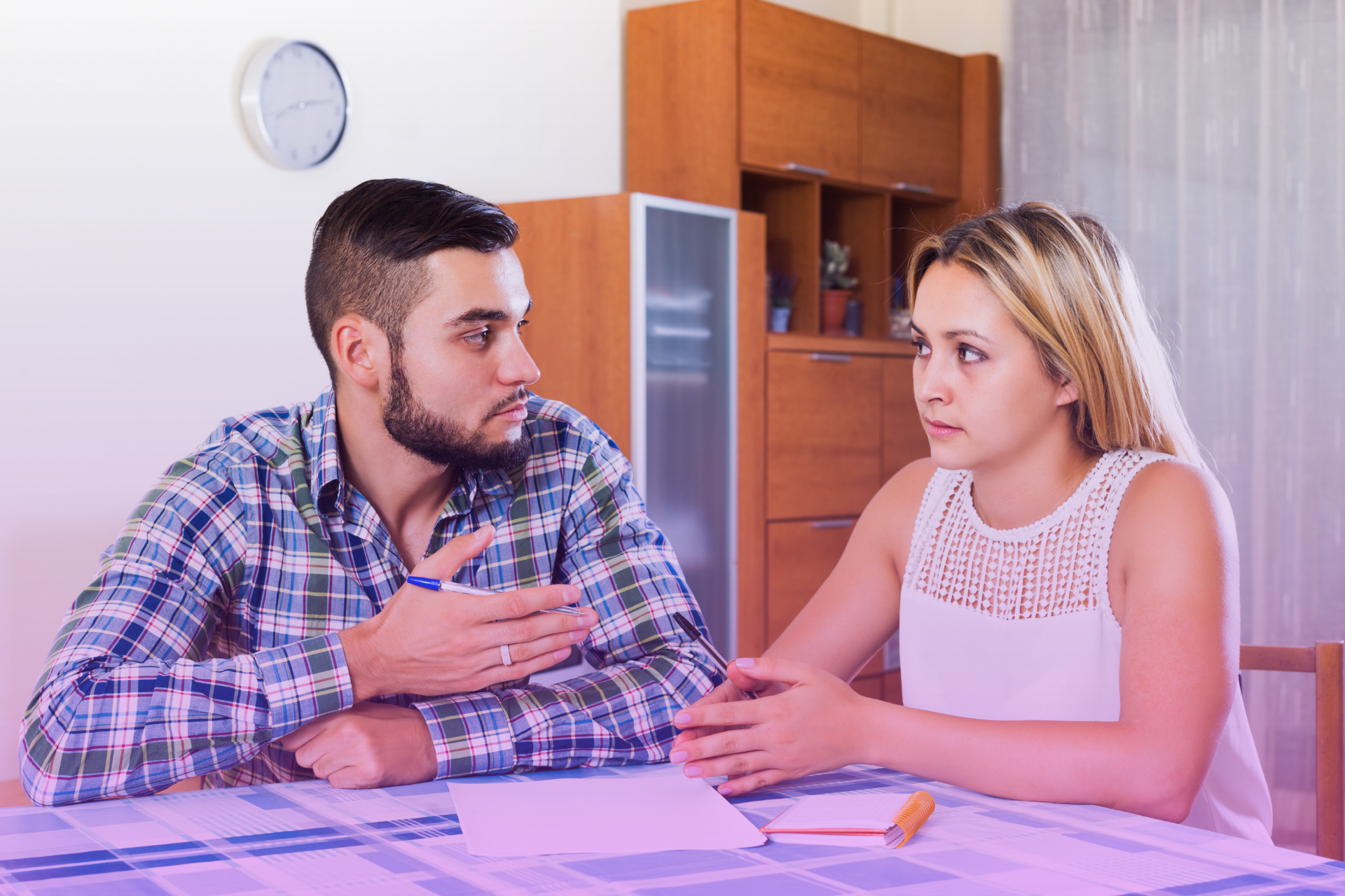 A California couple sitting on a couch, talking openly and smiling while reviewing financial documents.