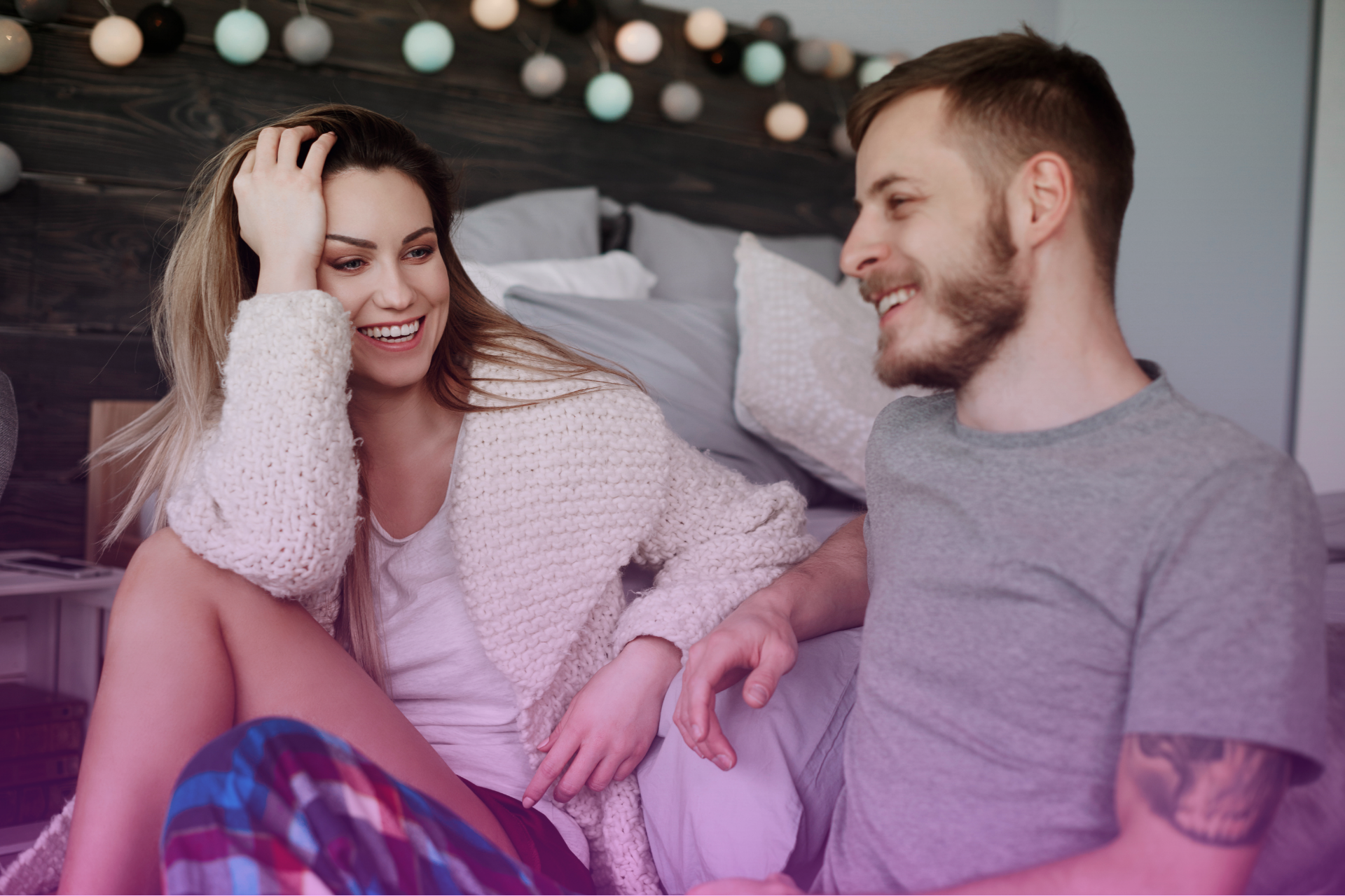 A happy couple sitting on a couch and talking openly while discussing a prenuptial agreement.