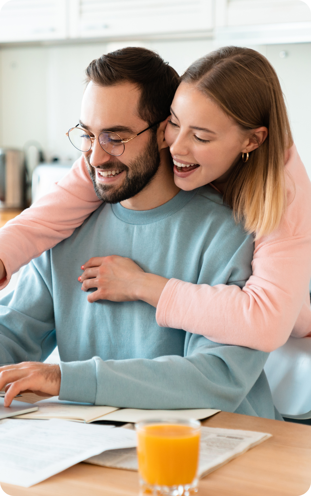 A couple smiling while looking at a computer screen together, sharing a joyful moment.
