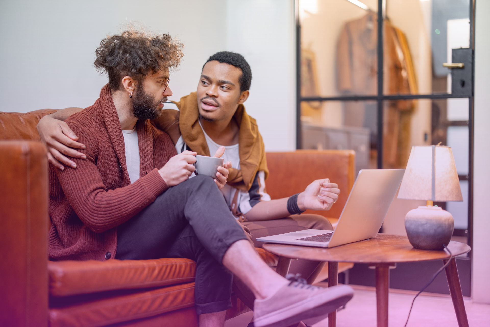 A relaxed couple sitting on a couch, smiling and talking openly with each other.