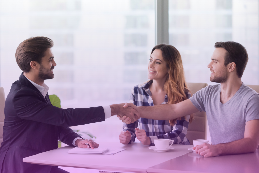 A couple sitting at a table with a lawyer, discussing documents, symbolizing a postnuptial agreement consultation.