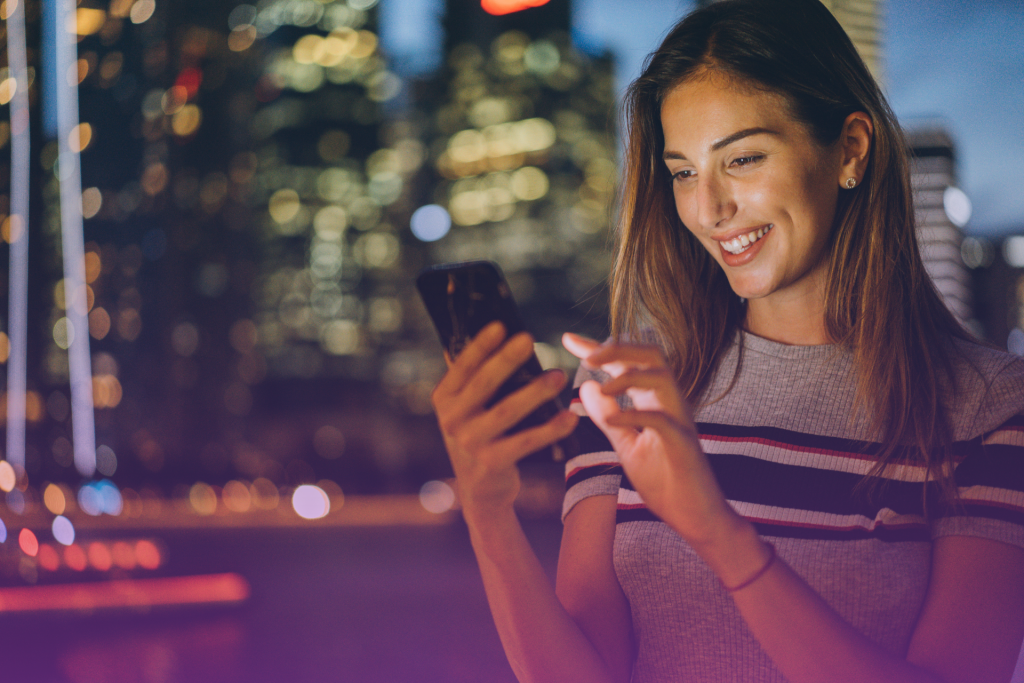A woman casually texting on her phone with a mischievous smile, hinting at a flirtatious conversation.