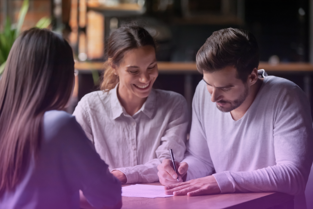 A happy couple talking openly and smiling while looking at financial documents, possibly discussing a postnuptial agreement.