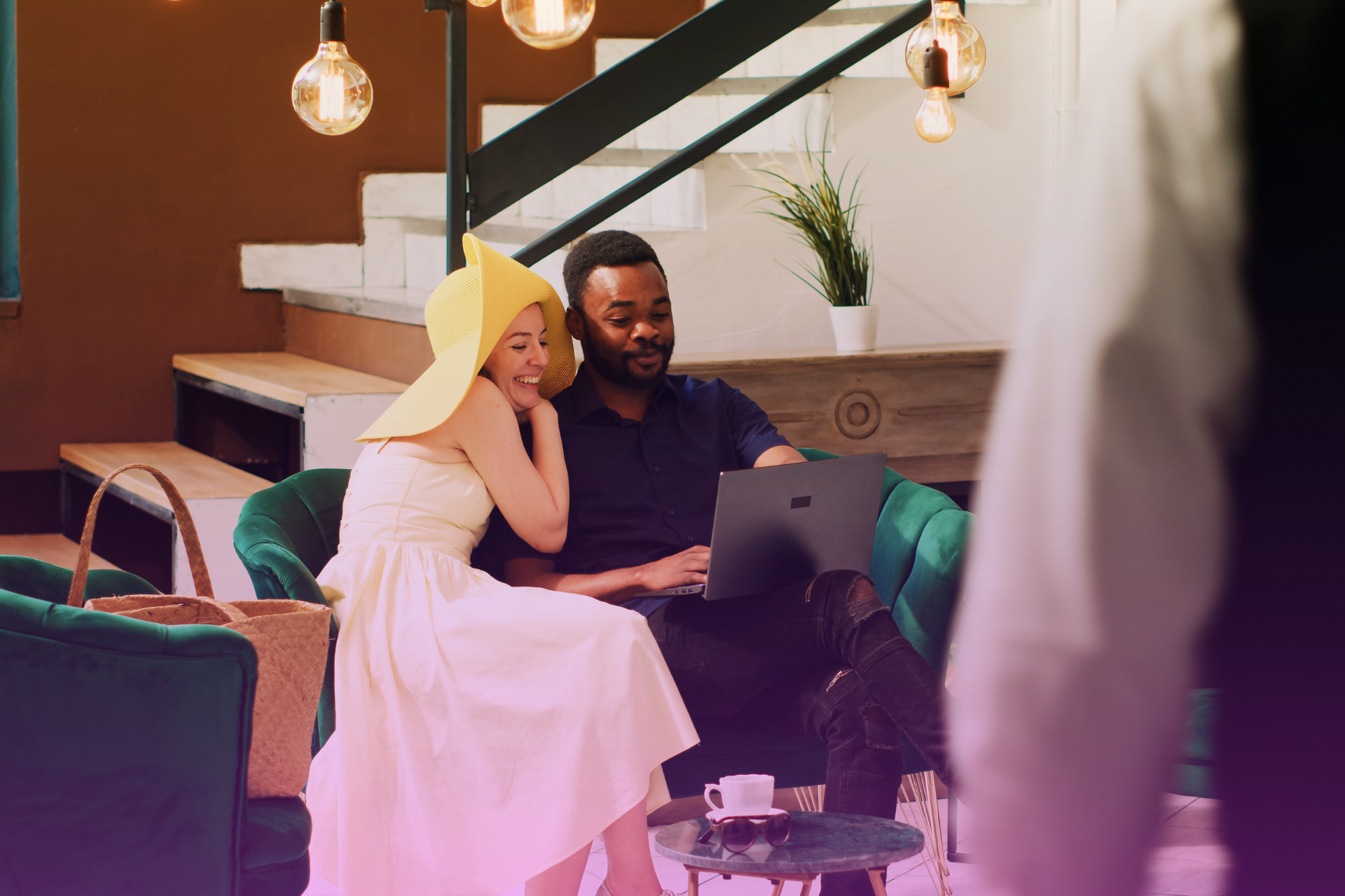 A happy couple holding hands while looking at financial documents in a laptop, suggesting a discussion about a prenup.