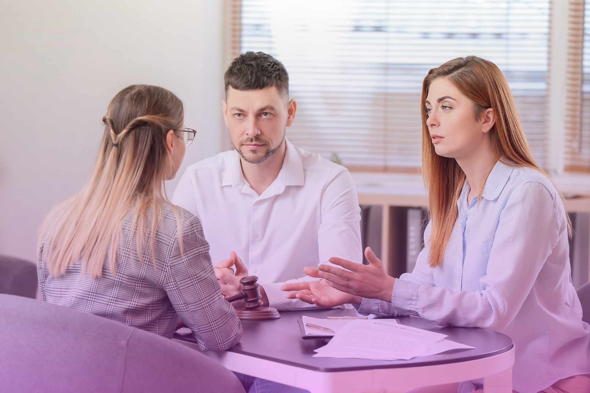 A happy couple sitting at a table with a lawyer, reviewing and discussing different clauses in a postnuptial agreement.