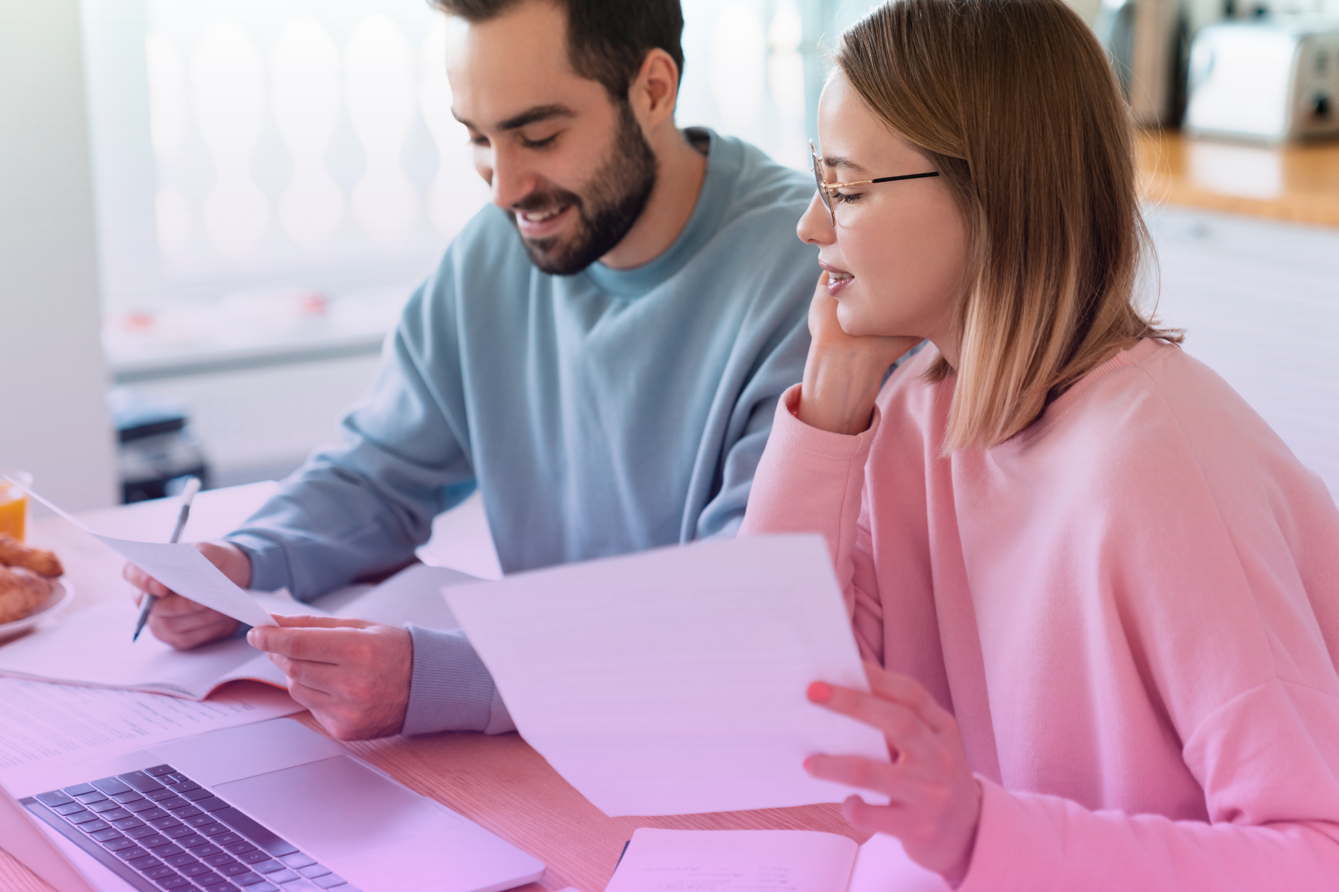 A happy couple sitting together at home, reviewing a document and discussing questions about their postnuptial agreement.