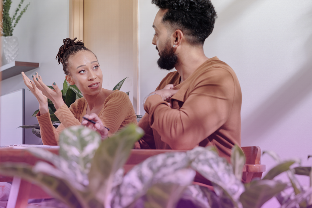 A happy couple sitting at a table, reviewing documents and discussing the steps to creating a postnuptial agreement.