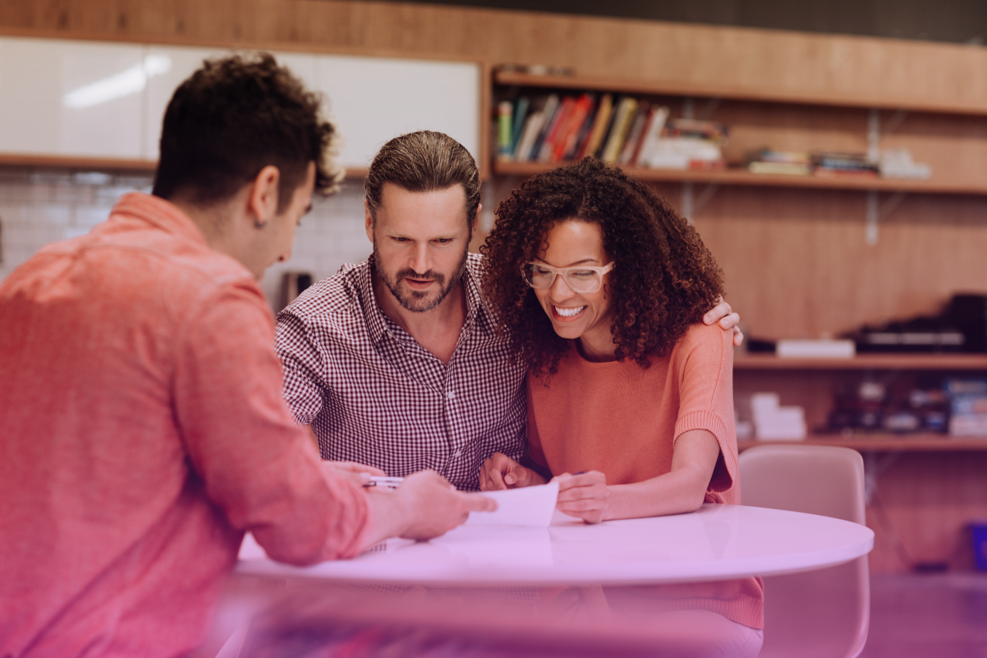 couple-signing-postnup-agreement A happy couple signing a postnuptial agreement with a lawyer present.