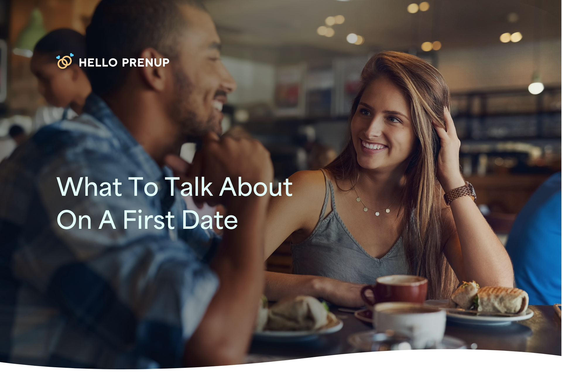 Two people on a first date smiling and laughing while talking at a cafe table.