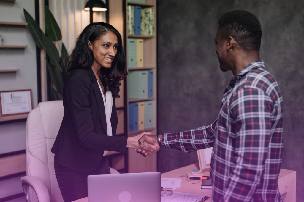 Two people shaking hands with a lawyer after signing a document, symbolizing a collaborative postnup agreement and successful lawyer selection.