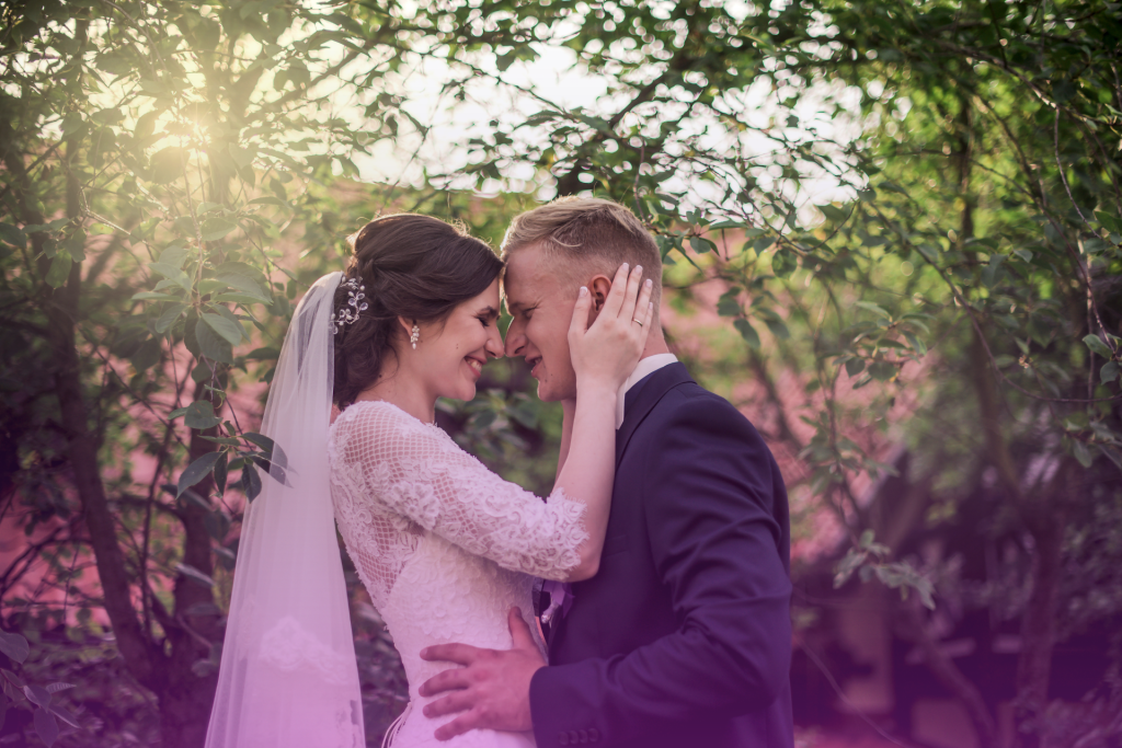 A joyful newlywed couple on their wedding day, gazing into each other's eyes with happiness.