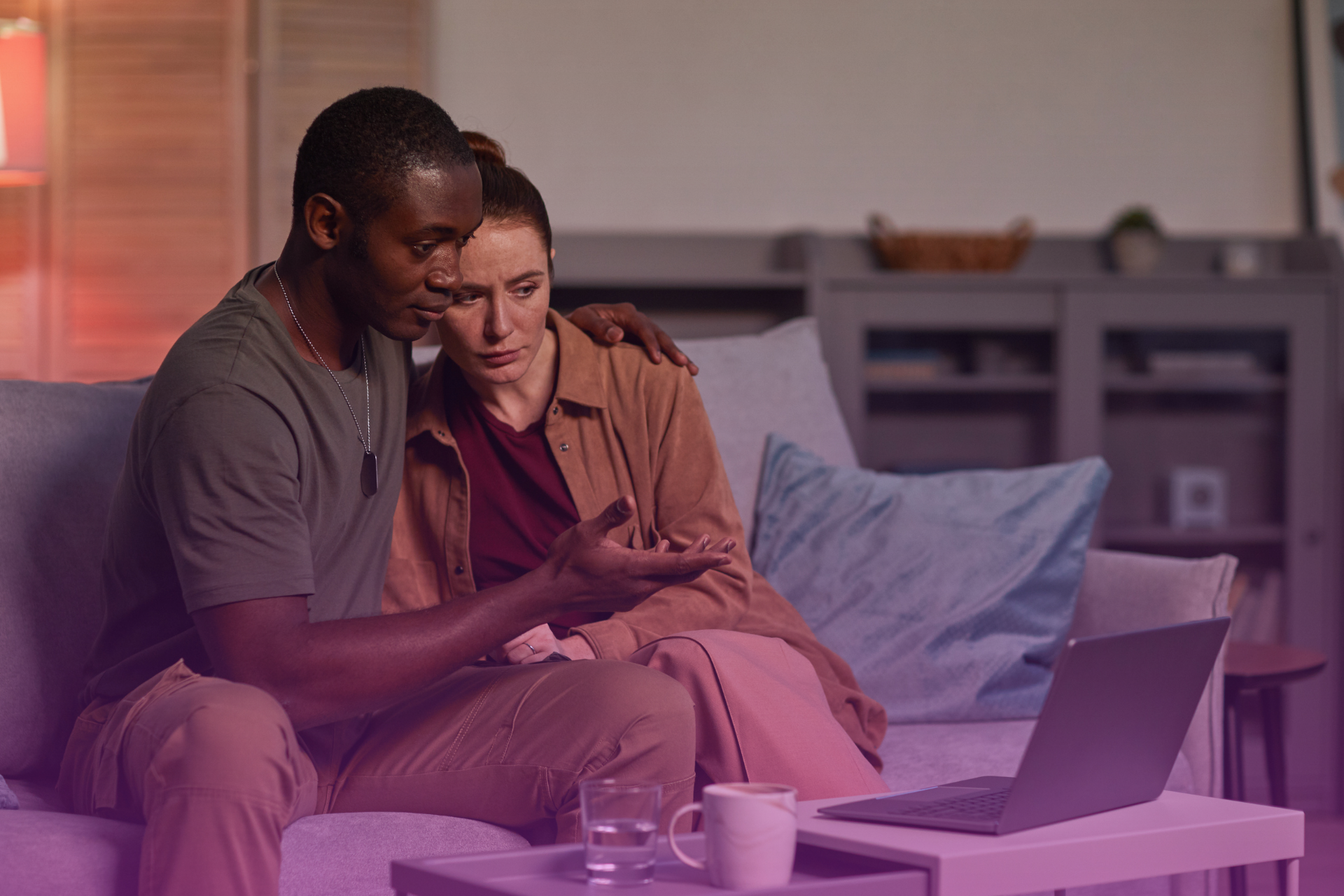 A couple sitting on a couch, engaged in a serious discussion about their future and financial plans, potentially related to updating their postnuptial agreement.