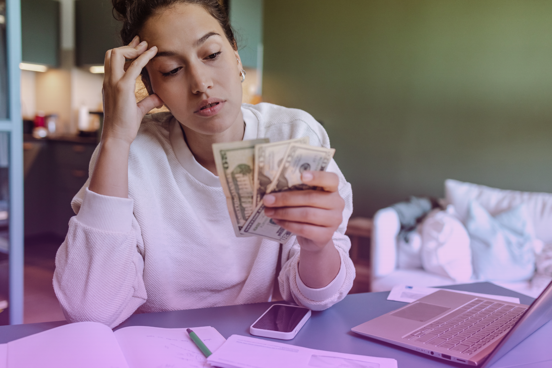 A person looking thoughtfully at a financial spreadsheet or documents, symbolizing financial considerations.