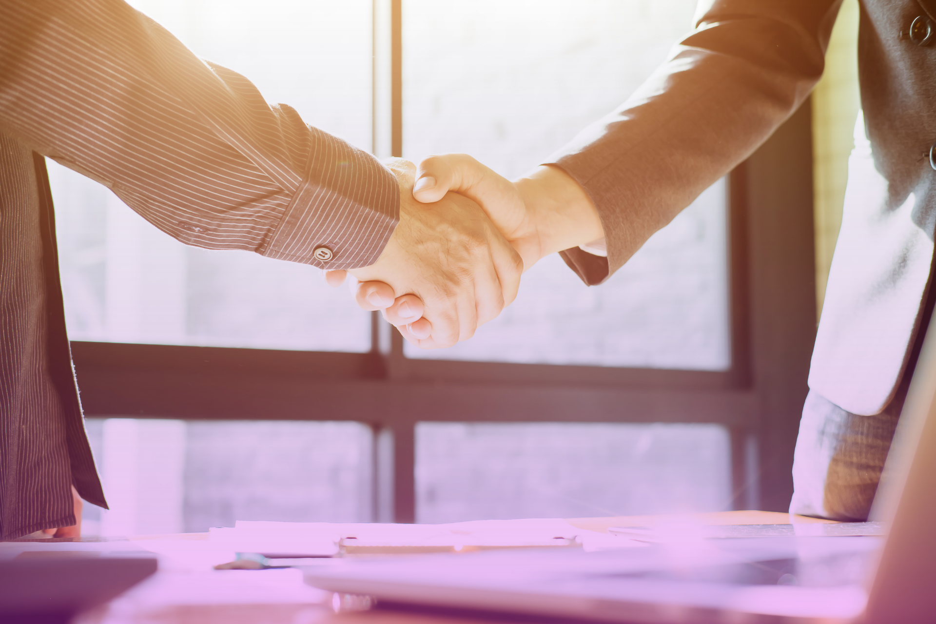 Two hands shaking firmly across a table, representing a fair and mutually agreed-upon resolution.