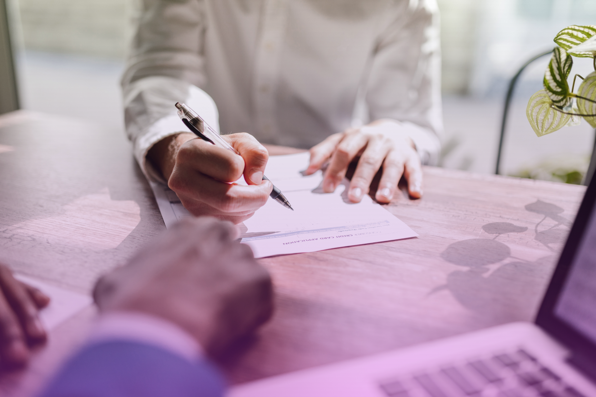 A person signing a legal document, with two other individuals observing as witnesses, representing the formal execution and validation process.