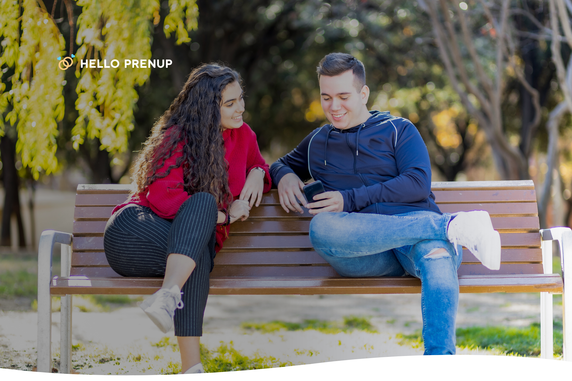 A couple is shown laughing together while sitting on a park bench, symbolizing how a prenup conversation can still be positive and relaxed.