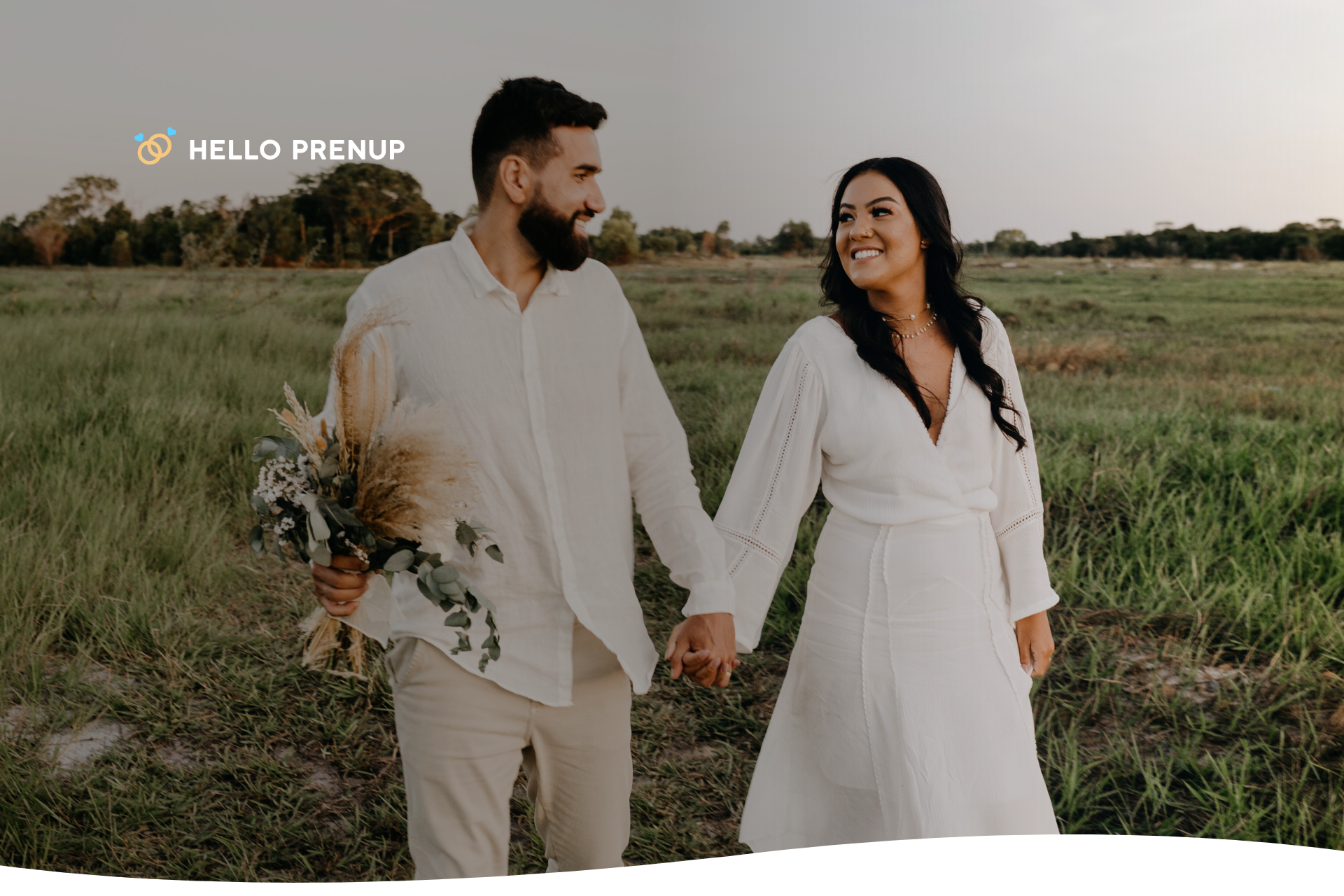 A couple is smiling and holding hands while walking in a park, representing the outward sign of a healthy and happy emotional connection.