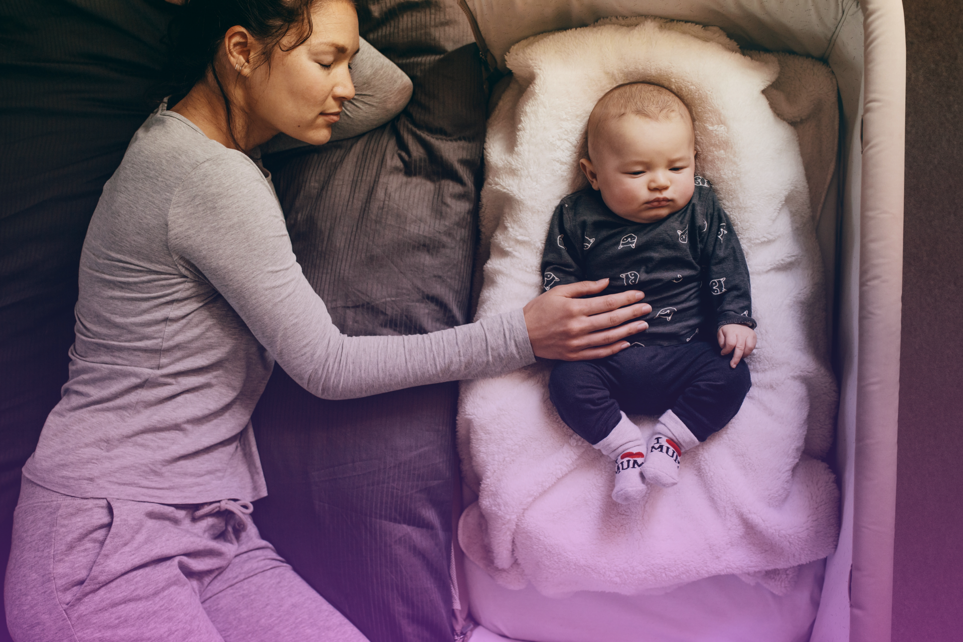 A man and woman looking stressed and exhausted with a baby sleeping in a carrier between them, representing the toll of sleep deprivation and stress.