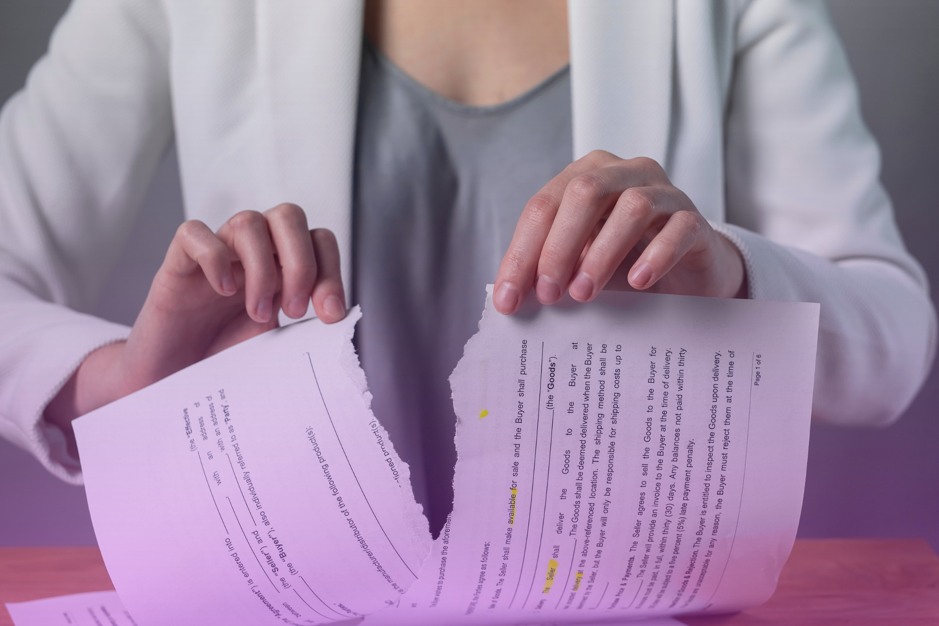 A person's hands symbolically ripping a document, representing the termination or cancellation of an agreement.