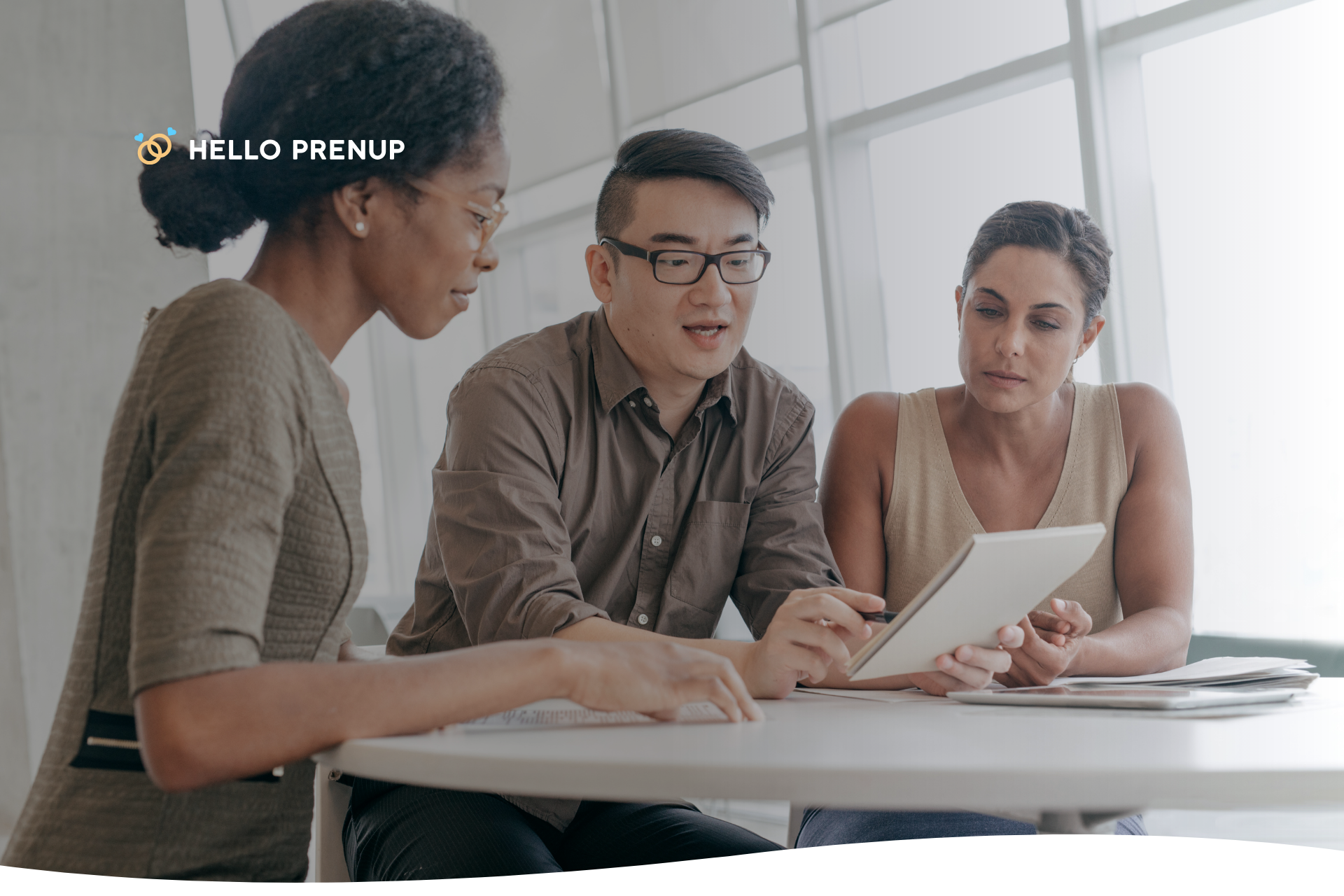 A couple is shown looking at a prenup document on a tablet with their lawyer, representing the need for professional legal advice
