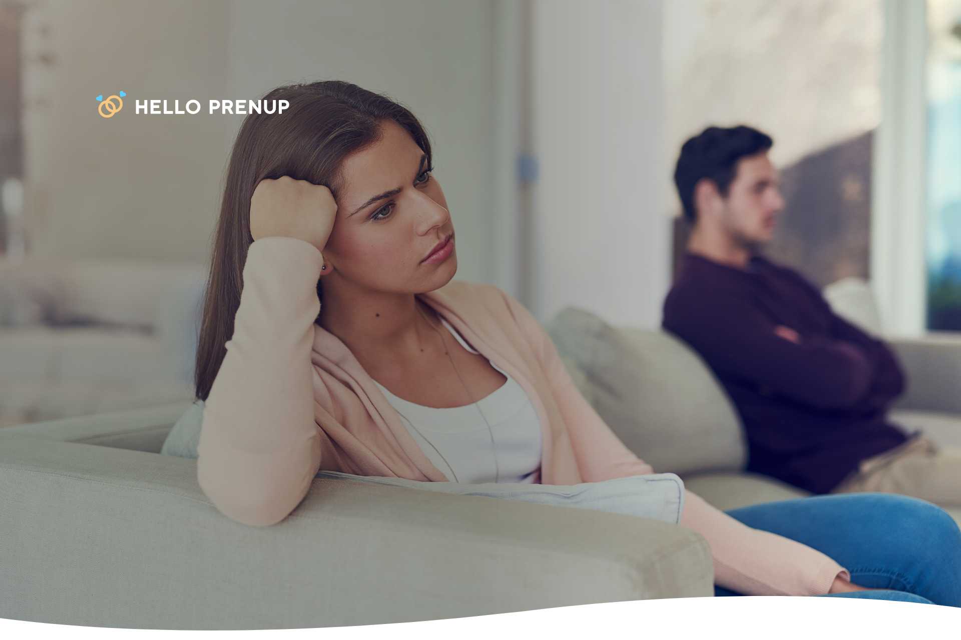 A couple sits on opposite ends of a long sofa, demonstrating emotional distance and disconnection.