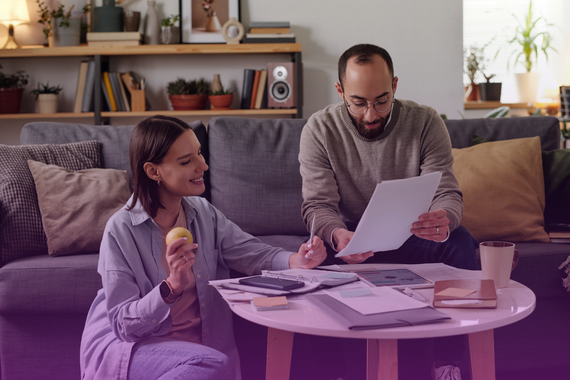 A couple sitting at a table with a large stack of papers, looking relieved, symbolizing the successful completion of a complex legal process.
