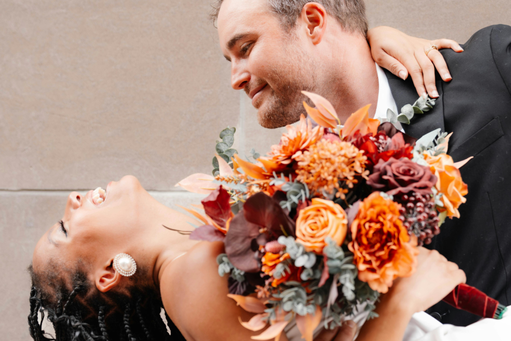 A bride and groom gazing into each other’s eyes while dancing, with the groom lifting the bride in his arms.