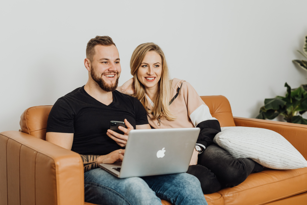 A couple sitting on a couch with a laptop on their laps, reviewing information together for a blog about the legal framework governing trusts.