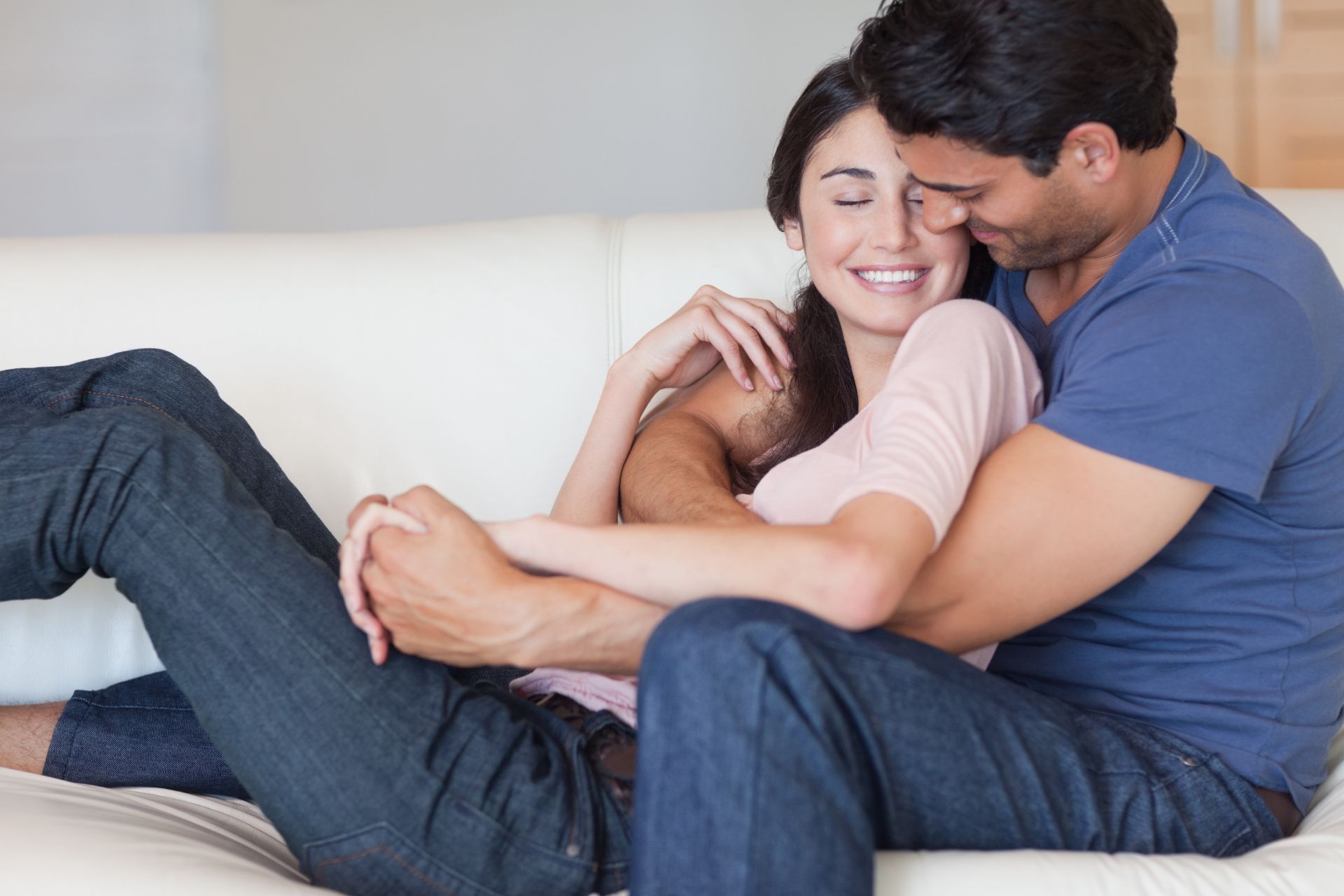 Couple embracing on a cozy sofa at home A couple sits closely together on a sofa, wrapped in a warm embrace and sharing a peaceful, intimate moment.