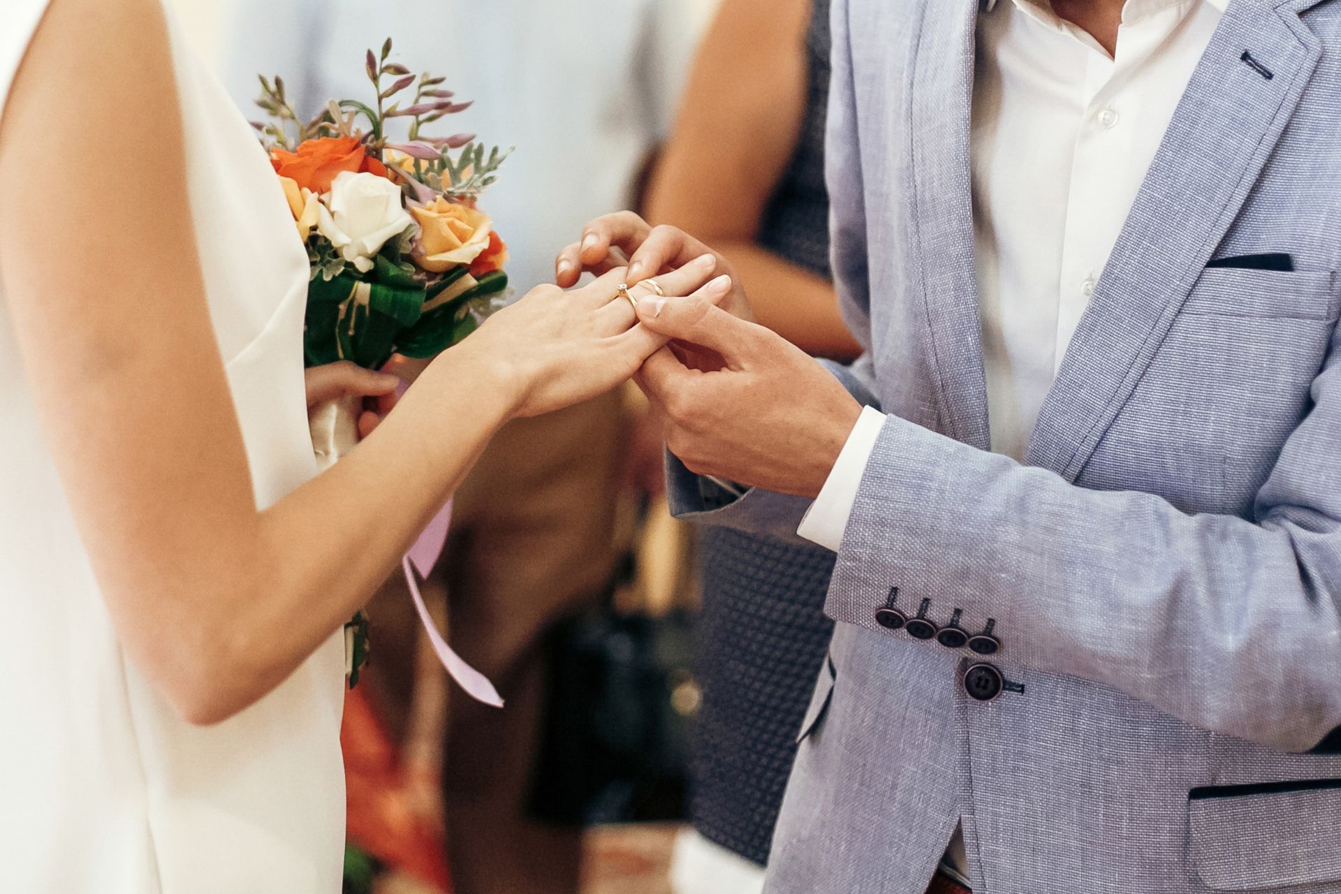 Groom Placing Wedding Ring During Registry Ceremony A couple at a civil registry wedding ceremony, with the groom gently placing a wedding ring on the bride’s finger as they stand together exchanging vows.