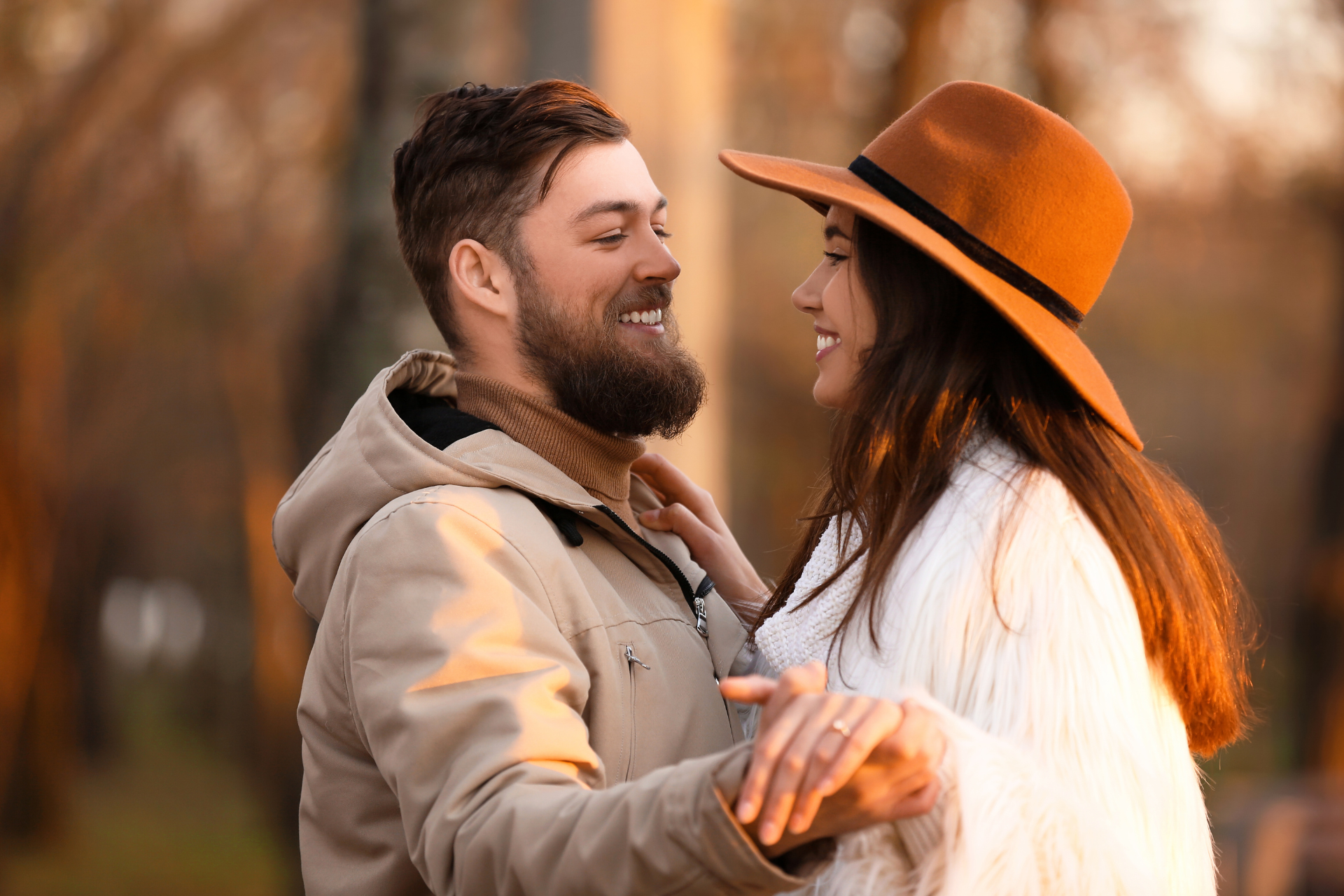 A romantic couple looking deeply into each other's eyes while dancing outdoors on a beautiful autumn day.