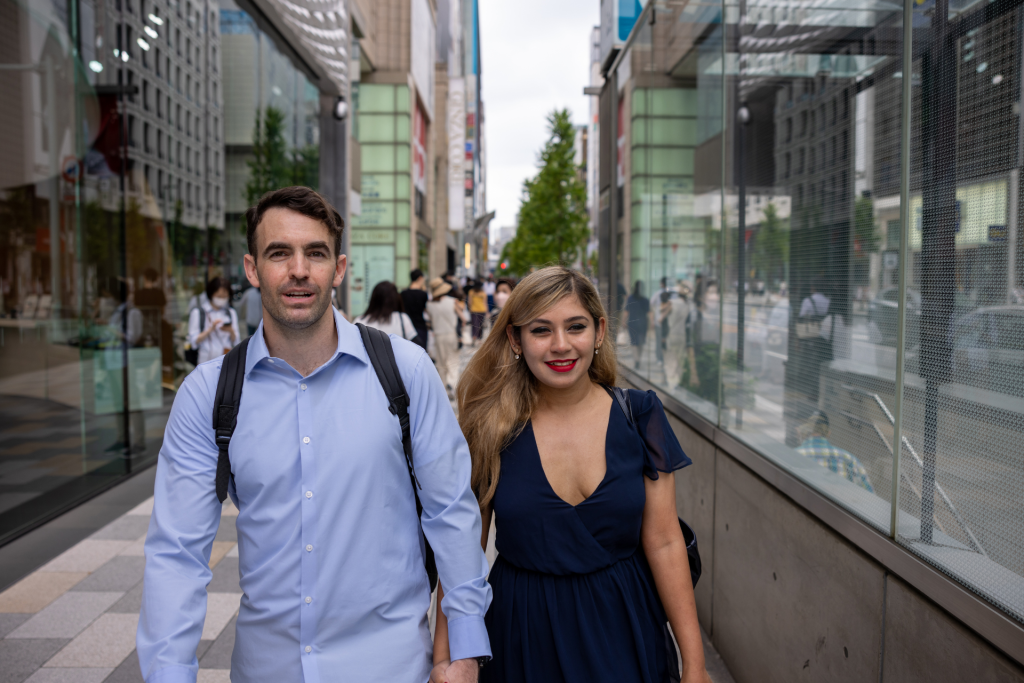 A couple holding hands while walking through the city on a sunny day, with the woman appearing Latina, capturing a warm and relaxed moment together