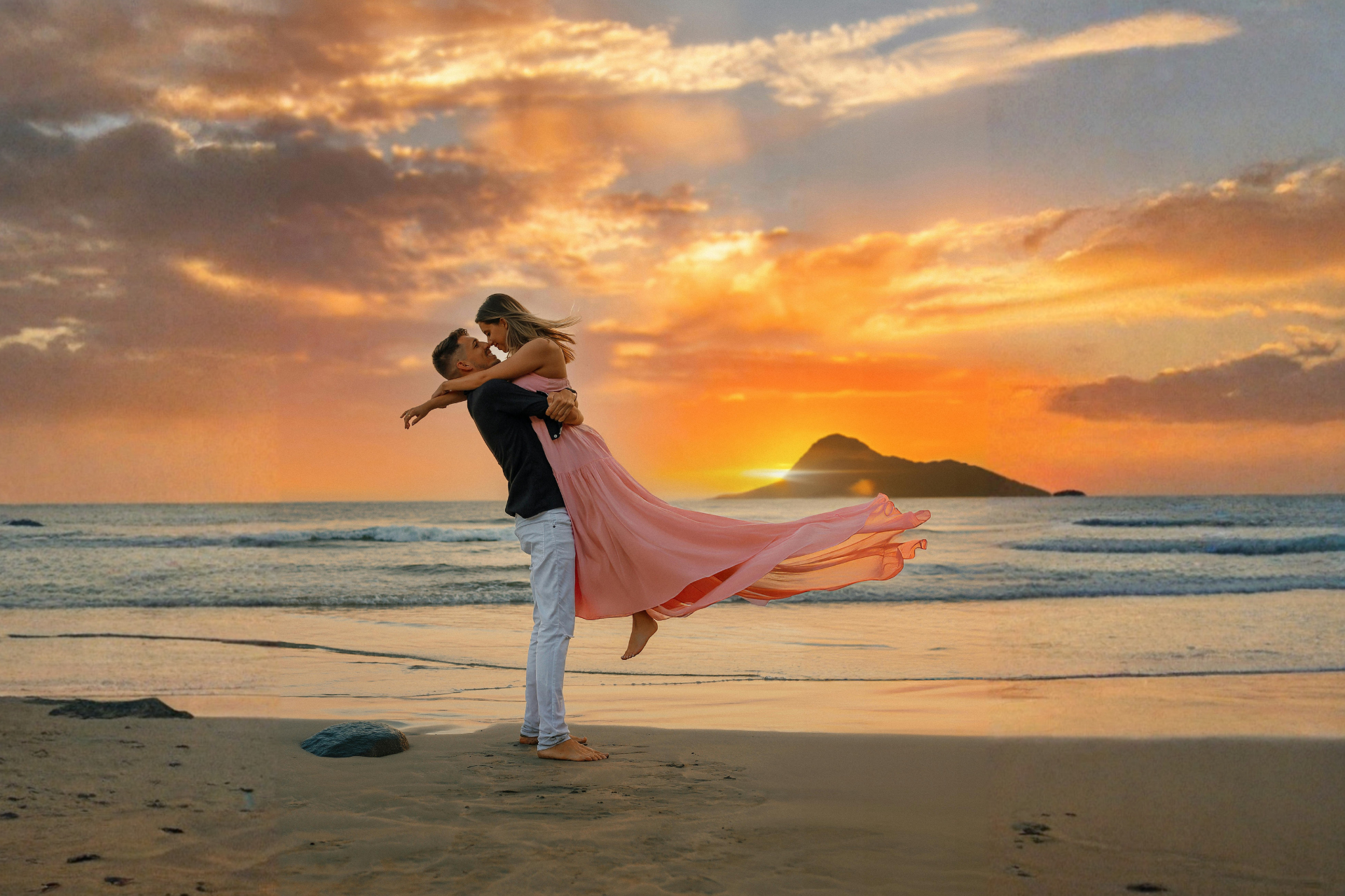 A couple on the beach at sunset, with the man holding the woman in his arms